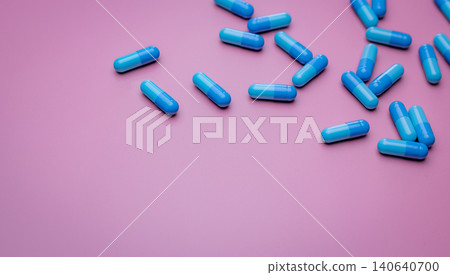 Top view capsule pills on pink background. Prescription drugs. Blue capsule pills. Pharmaceutical industry. Medicament and pharmacology. Drug development and new drug research. Capsule pills industry. 140640700