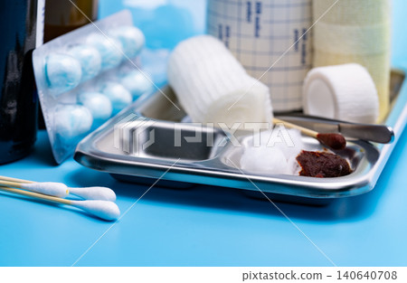 Wound care dressing set and stainless steel plate on blue background. Cotton ball and cotton stick with povidone-iodine for wounds, burns and cuts. Wound care supplies. Medical equipment for nurse. Wound care dressing set and stainless steel plate on blue background. Cotton ball and cotton stick with povidone-iodine for wounds, burns and cuts. Wound care supplies. Medical equipment for nurse. 140640708