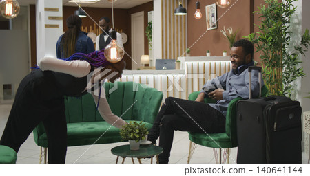 Guest reads texts on phone at reception, waiting for registration forms to do check in process and see room, male tourist using web browser on smartphone waiting to register at five star hotel. 140641144