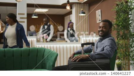 Hotel guest waiting in lobby for check in, sitting in lounge area reception next to luggage and preparing to see room. Hotel guest waiting in lobby for check in, sitting in lounge area reception next to luggage and preparing to see room. 140641227