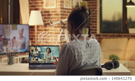 Woman meeting with clients on video call, explaining price list and services provided to build strong online career in freelancing, person using telework remote call at home, sunset light. 140641270
