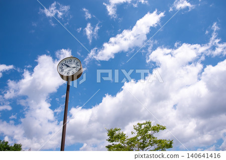A park clock and white clouds floating in the blue sky A park clock and white clouds floating in the blue sky 140641416