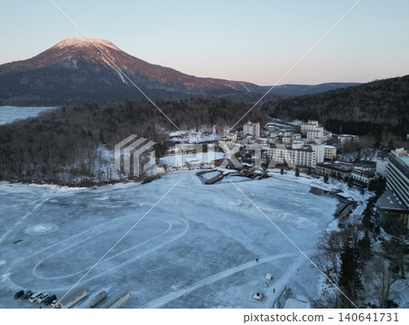 Aerial view of the frozen Lake Akan and the Akan Onsen hot spring resort area at sunset. Aerial view of the frozen Lake Akan and the Akan Onsen hot spring resort area at sunset. 140641731