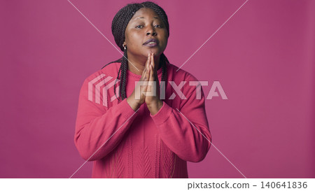 Young female earnestly begging with her hands together while looking at camera, with beautiful woman with body language of pleading and requesting. Young female earnestly begging with her hands together while looking at camera, with beautiful woman with body language of pleading and requesting. 140641836