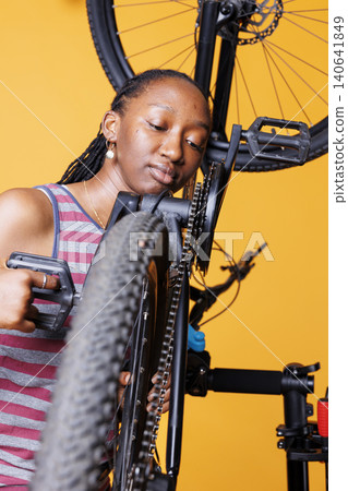 Woman closely analyzing bicycle chain with dedicated woman closely analyzing bike chain stay to maintain cycle efficiency. 140641849