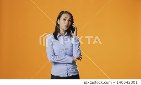 Relaxed person accepting calls in front of the lens interacting with friends on mobile telecoms connection, with in the studio, girl answers smartphone for remote conversation, chatting. Relaxed person accepting calls in front of the lens interacting with friends on mobile telecoms connection, with in the studio, girl answers smartphone for remote conversation, chatting. 140642001
