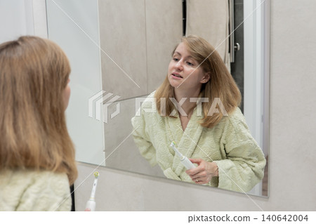 Smiling woman getting ready cheerfully, Female Caucasian excitedly practices her cheerful smile in bathroom, Joyful young woman readies herself with bright expression before leaving house Smiling woman getting ready cheerfully, Female Caucasian excitedly practices her cheerful smile in bathroom, Joyful young woman readies herself with bright expression before leaving house 140642004