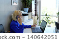 Professional woman in blue suit working at desk in office, using laptop and smartphone to manage business and multitask 140642051