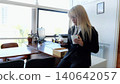 Confident businesswoman in stylish suit multitasks with coffee and smartphone in modern office, exuding elegance and professionalism 140642057