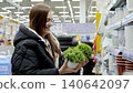 Happy shopper browsing small artificial potted plants in the gardening aisle of a major supermarket, finding joy in home decor shopping 140642097