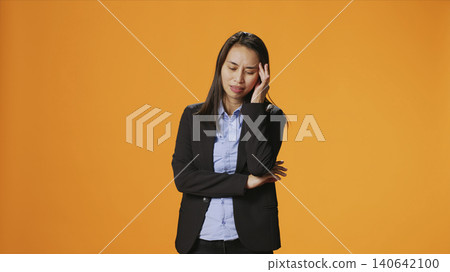 Business manager deals with tension and headache in studio, rubbing temples to ease pain, with young woman feeling unwell with painful migraine, working under stress and experiencing burnout. Business manager deals with tension and headache in studio, rubbing temples to ease pain, with young woman feeling unwell with painful migraine, working under stress and experiencing burnout. 140642100