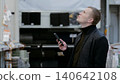 Man using smartphone to locate items on top shelves in hardware store. A man in a hardware store, choosing flooring, shelves with ceramic tiles. 140642108