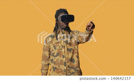 Cool man using virtual reality glasses in studio, enjoying 3d vision and interactive simulation vr headset on camera, with modern person having fun with goggles, artificial intelligence concept. Cool man using virtual reality glasses in studio, enjoying 3d vision and interactive simulation vr headset on camera, with modern person having fun with goggles, artificial intelligence concept. 140642157