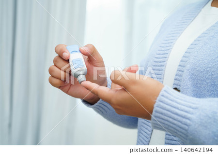 Asian woman self testing to check blood sugar level diabetes by digital lancet on finger at home. Asian woman self testing to check blood sugar level diabetes by digital lancet on finger at home. 140642194