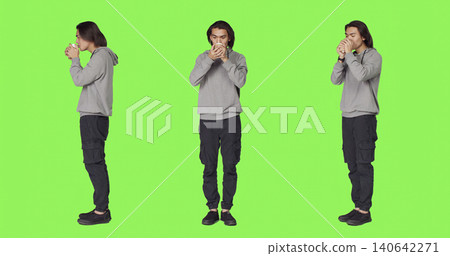 Person drinking coffee on camera, holding cup of hot caffeine beverage over full body green screen template, with young man enjoying refreshment and feeling positive in studio. Person drinking coffee on camera, holding cup of hot caffeine beverage over full body green screen template, with young man enjoying refreshment and feeling positive in studio. 140642271