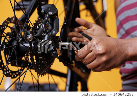 Person expertly repairing bicycle using expert work tool to adjust various components, with photo focus on hand grasping adjustable multitool for bike maintenance. 140642292