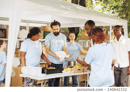 Empathetic service to the needy and poor multicultural team donates and provides humanitarian aid, with man with crutches receives assistance from black volunteer woman at food drive. Empathetic service to the needy and poor multicultural team donates and provides humanitarian aid, with man with crutches receives assistance from black volunteer woman at food drive. 140642332
