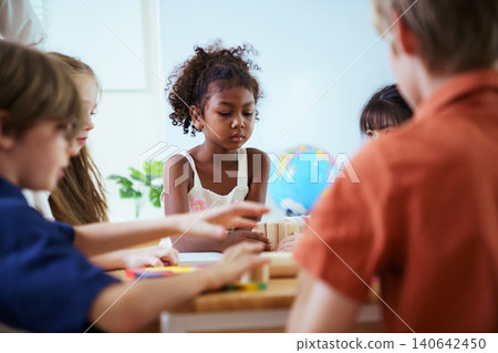 Excited black schoolgirl playing with wooden blocks in classroom Excited black schoolgirl playing with wooden blocks in classroom 140642450