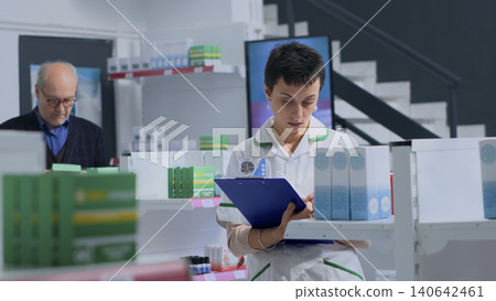 Customer in need of prescription medication information in drugstore, asking chemist checking pharmaceutical products inventory, with pharmacist helping client with recommendations. Customer in need of prescription medication information in drugstore, asking chemist checking pharmaceutical products inventory, with pharmacist helping client with recommendations. 140642461
