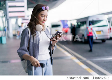 Asian woman traveler using smartphone with luggage at airport terminal Asian woman traveler using smartphone with luggage at airport terminal 140642898