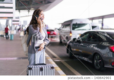 Asian woman traveler talking on smartphone at airport terminal Asian woman traveler talking on smartphone at airport terminal 140642901