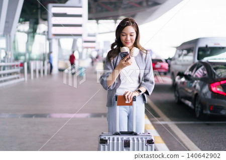 Asian woman traveler using smartphone with luggage at airport terminal Asian woman traveler using smartphone with luggage at airport terminal 140642902
