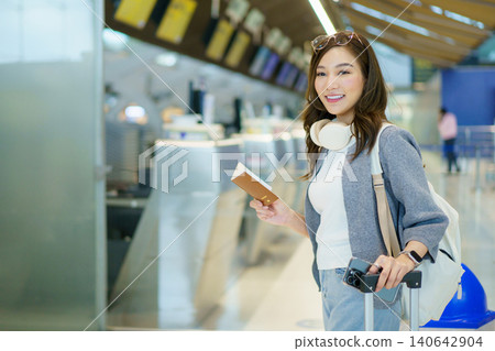 Asian woman traveler with suitcase using smartphone at airport check-in Asian woman traveler with suitcase using smartphone at airport check-in 140642904