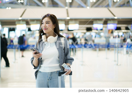 Asian woman traveler with suitcase using smartphone at airport check-in Asian woman traveler with suitcase using smartphone at airport check-in 140642905