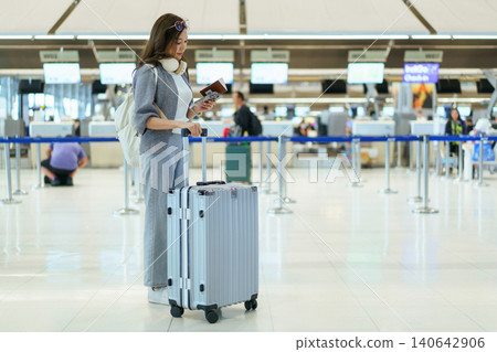 Asian woman traveler with suitcase using smartphone at airport check-in Asian woman traveler with suitcase using smartphone at airport check-in 140642906