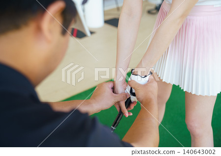 Golf coach correcting hand grip of a beginner golfer during a lesson. Golf coach correcting hand grip of a beginner golfer during a lesson. 140643002