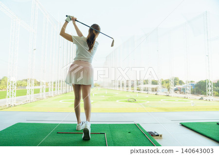 Woman golfer at driving range. Confidence practice and focused golf training. 140643003