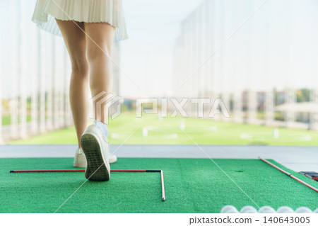 Back view of woman golfer lower body after swing at driving range. Back view of woman golfer lower body after swing at driving range. 140643005