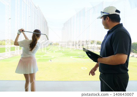 Golf instructor explaining swing technique on digital tablet to woman golfer at driving range. Golf instructor explaining swing technique on digital tablet to woman golfer at driving range. 140643007