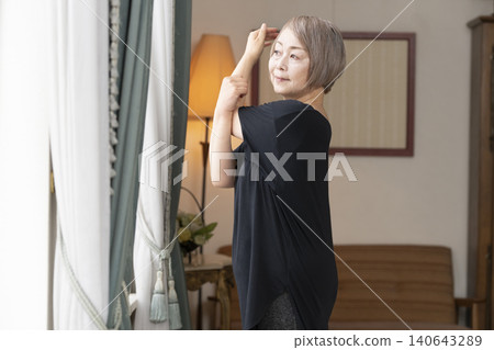 老婦人在客廳伸展身體 老婦人在客廳伸展身體 140643289