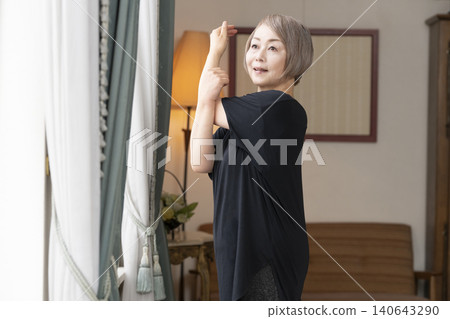 Senior woman stretching in the living room 140643290