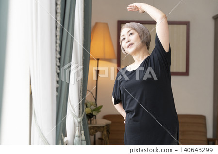 老婦人在客廳伸展身體 老婦人在客廳伸展身體 140643299