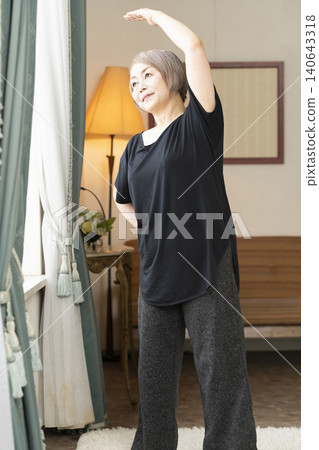 老婦人在客廳伸展身體 老婦人在客廳伸展身體 140643318