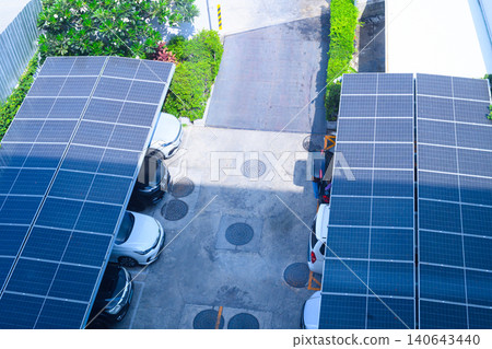 Top view of solar panel roofs over parked cars, sustainable energy use in a clean residential parking space Top view of solar panel roofs over parked cars, sustainable energy use in a clean residential parking space 140643440