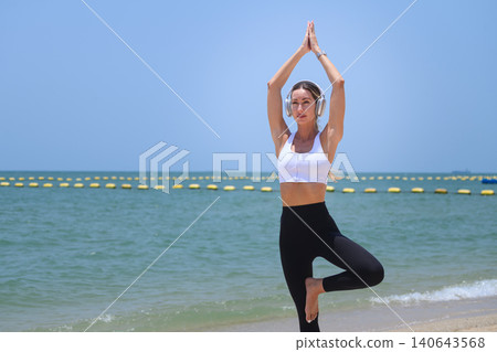 Calm woman practicing yoga meditation with raised hands on beach 140643568