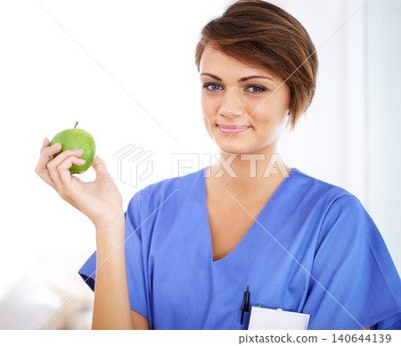 Woman, nurse and smile portrait with apple in medical office, nutrition and healthy food choice, professional nursing career. Dietician, healthcare and fruit for wellness with fibre and vitamins Woman, nurse and smile portrait with apple in medical office, nutrition and healthy food choice, professional nursing career. Dietician, healthcare and fruit for wellness with fibre and vitamins 140644139