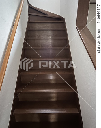 A staircase with a handrail leading to the second floor of a detached house. A staircase with a handrail leading to the second floor of a detached house. 140644157