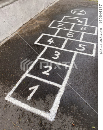 Traditional hopscotch game drawn with white chalk on wet dark asphalt. 140644187
