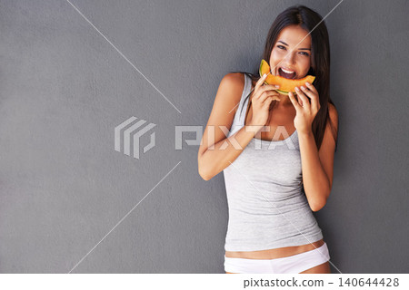 Slice of melon, portrait and woman with nutrition, wellness and person on a grey background. Face, model and girl eating a fruit, delicious or mockup space with diet plan and healthy snack with smile 140644428