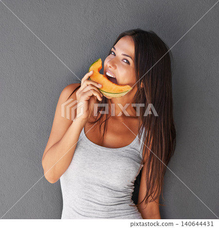 Slice of melon, portrait and woman with smile, nutrition and person on a grey background. Face, model and girl eating a fruit, wellness and mockup space with diet plan and healthy snack with treat 140644431