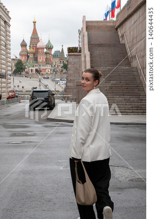 Woman in white blazer walks near Bolshoy Moskvoretsky Bridge in Moscow, Saint Basils Cathedral. Travel experience, sightseeing route, cultural heritage, city exploration, tourism content Woman in white blazer walks near Bolshoy Moskvoretsky Bridge in Moscow, Saint Basils Cathedral. Travel experience, sightseeing route, cultural heritage, city exploration, tourism content 140644435
