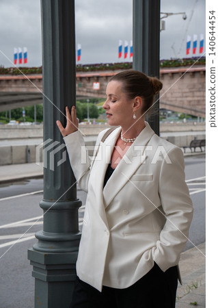 Woman stands beside colonnade on Sofiyskaya Embankment in Moscow, riverside roadway, city infrastructure, urban business, travel visual. Personal branding, corporate communication Woman stands beside colonnade on Sofiyskaya Embankment in Moscow, riverside roadway, city infrastructure, urban business, travel visual. Personal branding, corporate communication 140644454