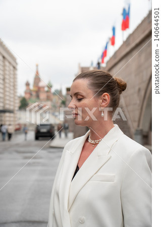 Woman in white blazer near Bolshoy Moskvoretsky Bridge, Moscow, Saint Basils Cathedral softly visible. Urban portrait, travel content, cultural heritage, city atmosphere, architectural backdrop Woman in white blazer near Bolshoy Moskvoretsky Bridge, Moscow, Saint Basils Cathedral softly visible. Urban portrait, travel content, cultural heritage, city atmosphere, architectural backdrop 140644501