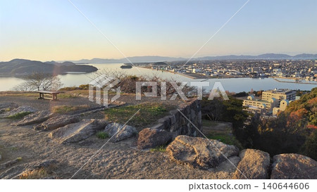 A spectacular panoramic view of the calm waters of Lake Nakaumi and the cityscape stretching out on the opposite shore, as seen from the castle tower base of Yonago Castle. A spectacular panoramic view of the calm waters of Lake Nakaumi and the cityscape stretching out on the opposite shore, as seen from the castle tower base of Yonago Castle. 140644606