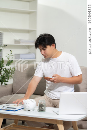 Concept with saving money, man working on desk in home using calculator and laptop to calculate budget. Concept with saving money, man working on desk in home using calculator and laptop to calculate budget. 140644823