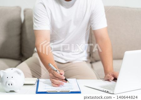 Concept with saving money, man working on desk in home using calculator and laptop to calculate budget. Concept with saving money, man working on desk in home using calculator and laptop to calculate budget. 140644824